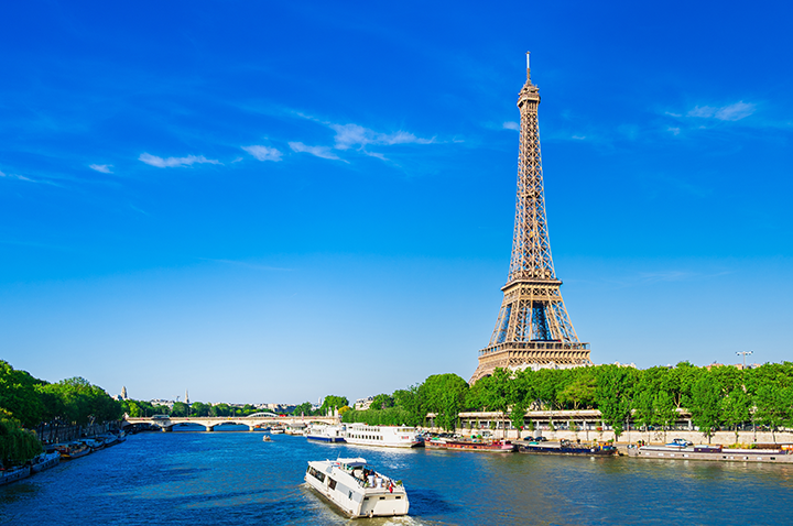 Ein Boot fährt den Fluss entlang, im Hintergrund ragt ein Turm über die Pariser Landschaft. Ein Boot fährt den Fluss entlang, im Hintergrund ragt ein Turm über die Pariser Landschaft.