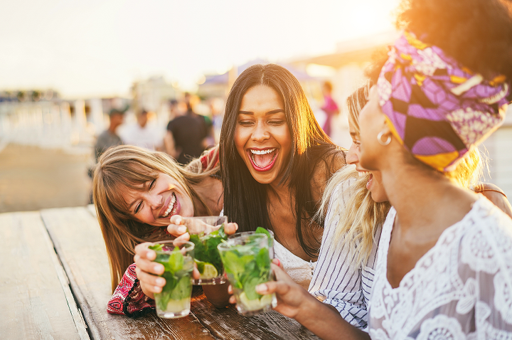 Vier Frauen genießen Cocktails auf einer fröhlichen Party und lachen miteinander. Vier Frauen genießen Cocktails auf einer fröhlichen Party und lachen miteinander.