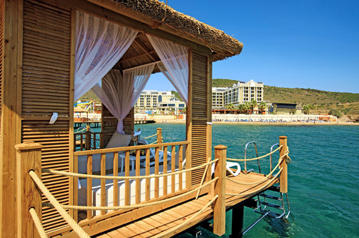 Charmantes Holzhaus auf dem Wasser mit einem schützenden Dach und das Hotel im Hintergrund, ideal für einen erholsamen Hotelaufenthalt Charmantes Holzhaus auf dem Wasser mit einem schützenden Dach und das Hotel im Hintergrund, ideal für einen erholsamen Hotelaufenthalt