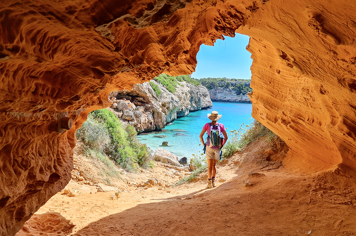 Eine Person geht durch eine Höhle am Strand, umgeben von Felsen und dem Klang der Wellen. Eine Person geht durch eine Höhle am Strand, umgeben von Felsen und dem Klang der Wellen.