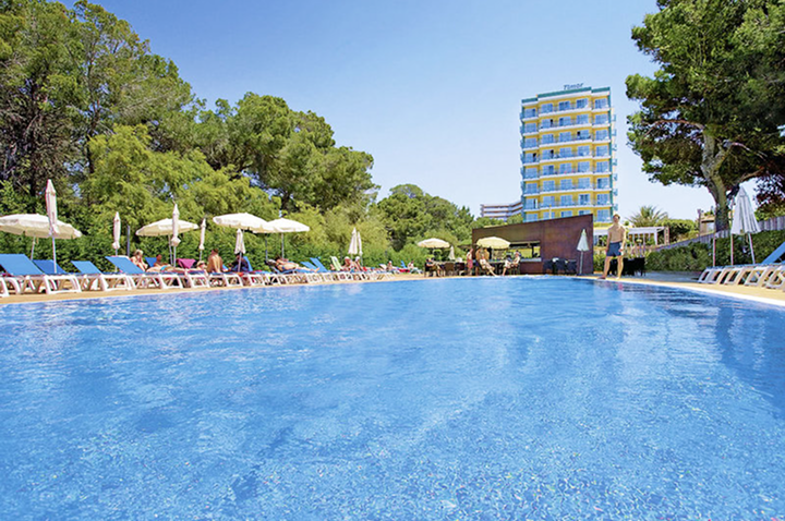 Großer rechteckiger Hotelpool mit Liegestühlen und Sonnenschirmen an den Seiten sowie einem mehrstöckigen Hotelgebäude im Hintergrund. Großer rechteckiger Hotelpool mit Liegestühlen und Sonnenschirmen an den Seiten sowie einem mehrstöckigen Hotelgebäude im Hintergrund.