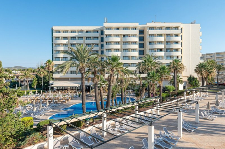 Ein Hotel umgeben von Palmen mit einem einladenden Swimmingpool im Vordergrund Ein Hotel umgeben von Palmen mit einem einladenden Swimmingpool im Vordergrund