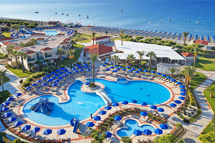 Luftaufnahme einer Hotelanlage mit mehreren Pools, Sonnenschirmen und Palmen am Strand. Luftaufnahme einer Hotelanlage mit mehreren Pools, Sonnenschirmen und Palmen am Strand.